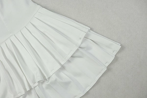 Detail of white pleated dress showing layered ruffles and textured premium fabric