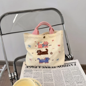 Détail du sac en velours beige avec broderie chat et bouton-pression en métal sûr