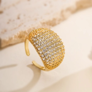 Macro shot of gold-plated open ring with shimmering pavé-set zircons on stone surface