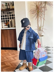 Detail view of a child wearing a colorful checkered canvas backpack with a denim outfit
