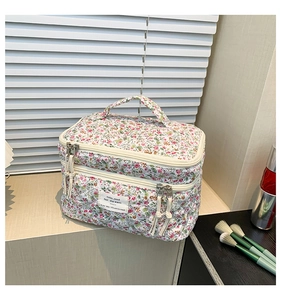 Floral double-layer quilted cotton makeup bag with handle on a beige surface