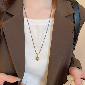 Detailed view of a gold spiral texture pendant necklace worn with professional attire