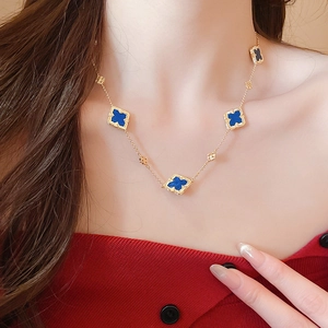 Close-up of gold-plated necklace with blue clover motifs on a model's neck