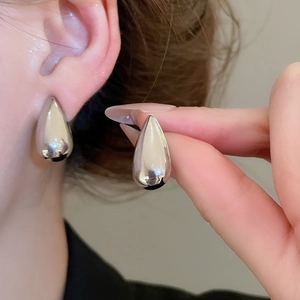 Close-up of polished silver teardrop earrings on model with high gloss metallic finish