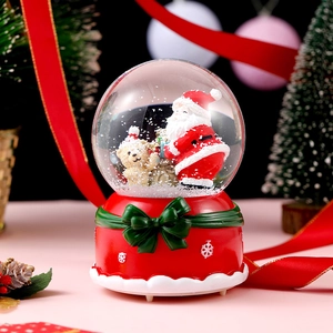 Macro shot of Christmas music box with Santa and bear figures inside a glass snow globe
