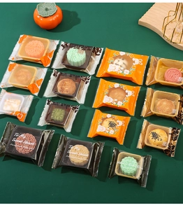 Flat lay of colorful mooncake packaging bags with festive decorations on green background
