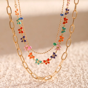 Macro shot of layered gold chain necklace featuring colorful enamel butterfly pendants
