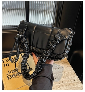 Détails de la texture matelassée noire et de l'élégante poignée plissée du sac à main