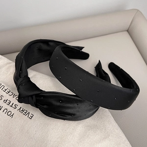 Detail of black satin headbands with small dots on a beige canvas background