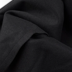 Gros plan détaillé de la texture du tissu en laine noire et des coutures de la robe en similicuir