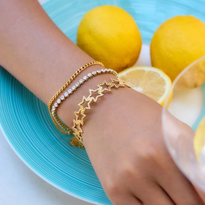 Detail von goldenem Sternarmreif mit Hammerschlag-Textur und glänzendem Tennis-Armband