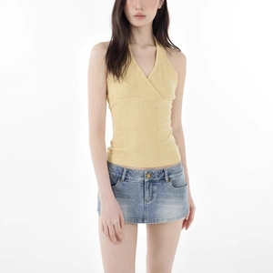 Detail of yellow halter knit top and distressed blue denim skirt set on model