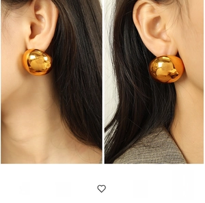 Close-up of oversized golden eggshell earrings with reflective metallic mirror finish