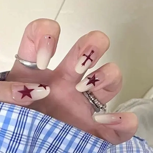 Almond shaped ombré press-on nails with dark red stars and minimalist cross patterns