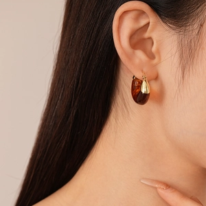 Close-up of brown marble resin hoop earrings with gold metal clasp on model