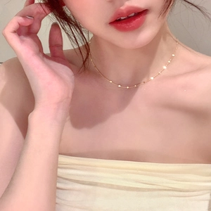 Gros plan d'un collier chaîne fine dorée avec sequins ronds sur le cou d'un mannequin