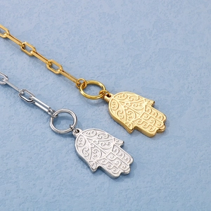 Detail of gold and silver Hamsa hand pendants on paperclip chain bracelets