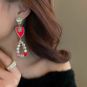 Detailed view of long gold tassel earrings featuring red heart and rhinestone waterdrop
