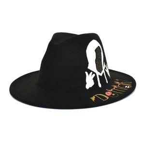 Detail of black wool fedora featuring white hoodie graphic and gold Demon text on brim