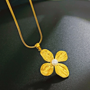 Detailed close-up of a gold clover pendant necklace featuring a white pearl inlay