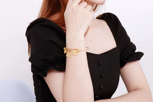 Detail of gold charm bracelet with I Love Mom heart pendants on female model wrist