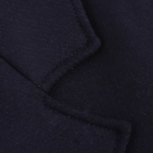 Detailed close-up of dark blue wool coat fabric showing fine stitching and premium texture