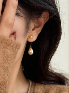 Detailed view of French vintage gold teardrop pearl earrings worn on the ear model