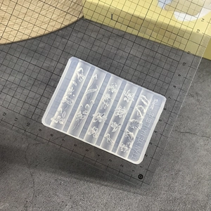 Detailed view of clear silicone nail art mold with floral patterns and measurement ruler