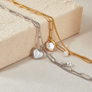 Detail of silver and gold double-layered heart necklaces with pearls and tassels