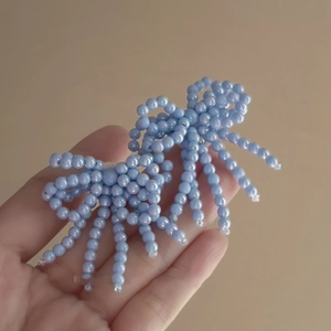 Detail of light blue beaded bow earring showing the delicate handmade craftsmanship
