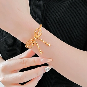 Close-up of elegant gold bow bracelet on wrist highlighting refined metallic texture