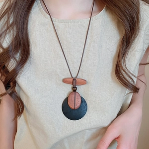 Close-up of ethnic necklace with brown wooden pendants on light linen shirt