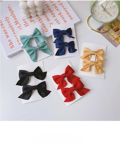 Flat lay of colorful bow hair clips in five colors on a decorative white tabletop