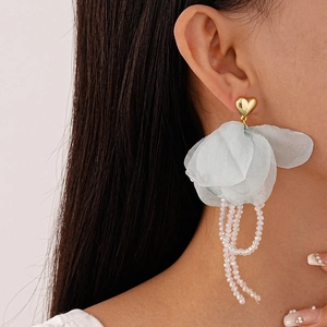 Détail de boucles d'oreilles fleur en dentelle bleue avec pompons en cristal