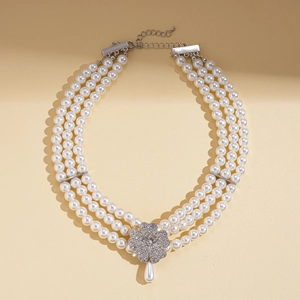 Close-up of multilayer pearl necklace with a rhinestone flower and teardrop pearl pendant