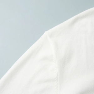 Close-up of white knitted cardigan featuring premium shoulder seam and fine fabric texture