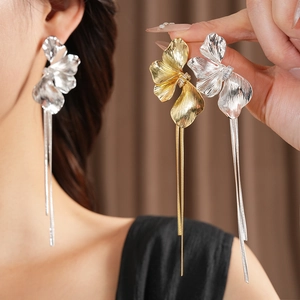 Makroansicht goldener und silberner Blumenohrringe mit eleganten langen Metallquasten