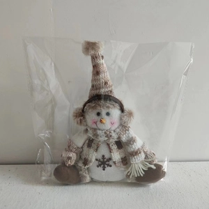 Detail of Christmas snowman plush toy with knitted hat and snowflake embroidery in plastic bag