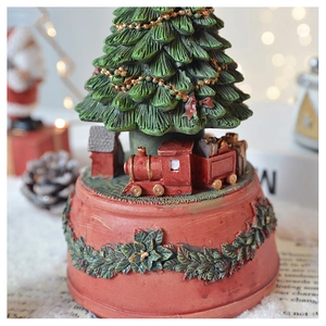 Detail of Christmas tree music box with a red train and holly berry embossed base