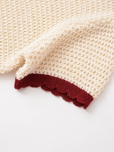 Macro detail of honeycomb crochet knit texture with contrasting burgundy wavy edge finish