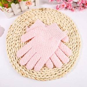Pink exfoliating bath gloves with grainy texture displayed on a rustic woven mat