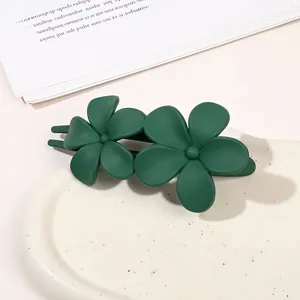 Close-up of matte dark green double flower hair clip on a minimalist display tray