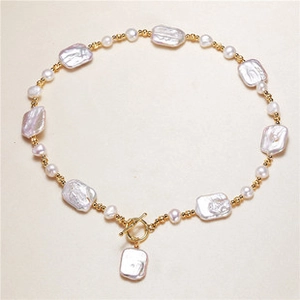 Detailed close-up of Baroque pearl necklace with gold beads and OT toggle clasp closure