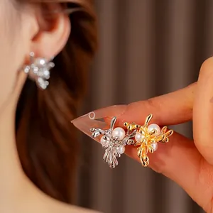 Elegante Perlenohrringe in Blumenform mit Metallzweigen am Modell und in der Hand