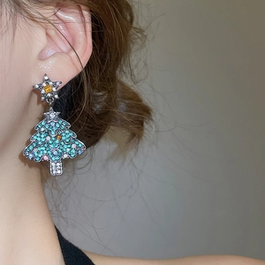 Gros plan de boucles d'oreilles sapin de Noël scintillantes avec strass colorés sur modèle
