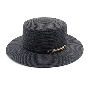 Détail d'un chapeau de paille noir avec ruban en cuir et boucle métallique dorée