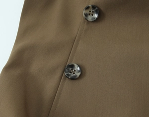 Detailed close-up of tortoise shell buttons and stitching on khaki sleeveless top