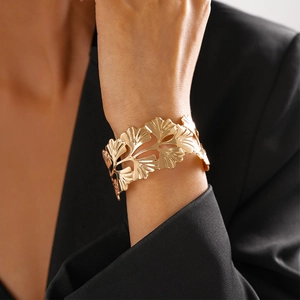 Détail d'un bracelet manchette doré à feuilles de ginkgo ajourées sur un mannequin