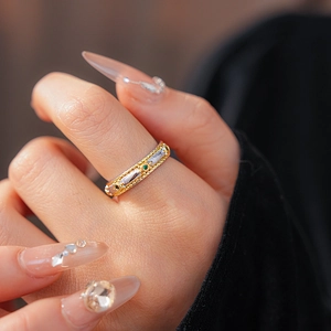 Macro shot of vintage bicolor oval ring with green and black gemstones on finger