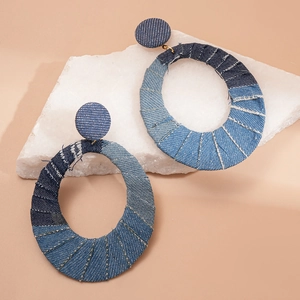 Detail view of oval denim fabric earrings with blue gradient layers on stone